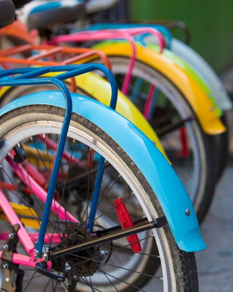 Close-up of brightly colored bicycle fenders (blue, pink, yellow) parked on a street in Guatapé, symbolizing the town's vibrant style.
