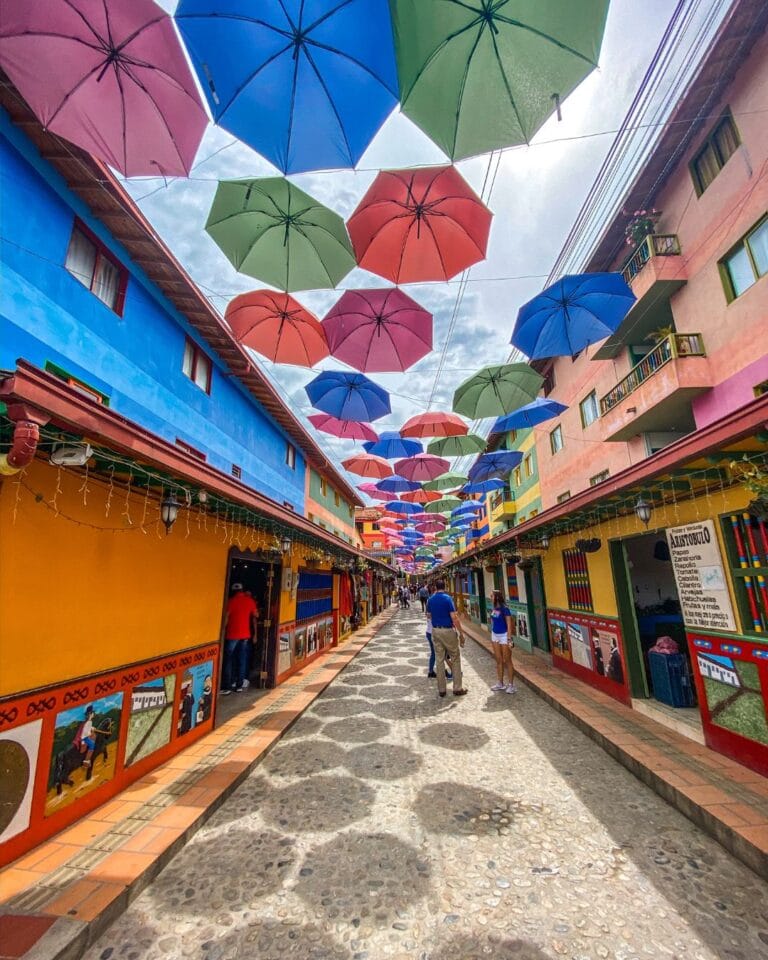 The famous Calle del Recuerdo in Guatape, featuring colorful Zócalo architecture and an overhead canopy of suspended umbrellas.